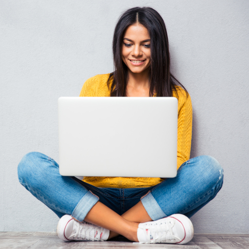 Young woman looking at laptop while sitting on floor_500